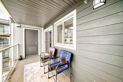 The balcony features a clear glass railing, a solid grey door, and siding with horizontal panels - 307 9504 182 Street Nw, Edmonton, AB - Outdoor With Exterior