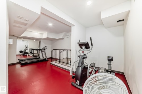 This property features a dedicated fitness area with red flooring and white walls, offering various exercise equipment - 307 9504 182 Street Nw, Edmonton, AB - Indoor