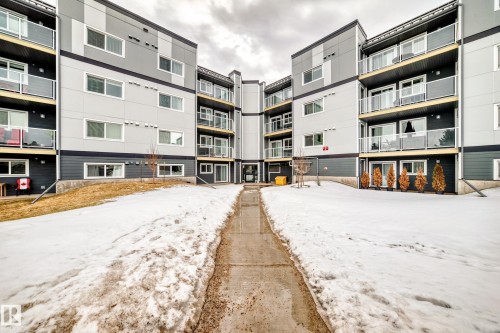 The property features a modern exterior with a grey and dark grey facade, white-trimmed windows, and balconies with glass railings - 307 9504 182 Street Nw, Edmonton, AB - Outdoor With Balcony With Facade