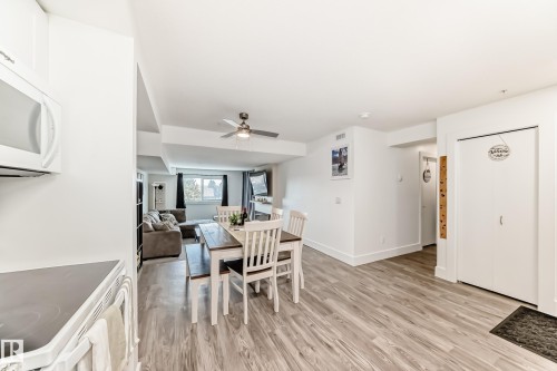 Open concept living space featuring wood-look flooring, a ceiling fan, and a dining area with a table and seating - 307 9504 182 Street Nw, Edmonton, AB - Indoor Photo Showing Dining Room
