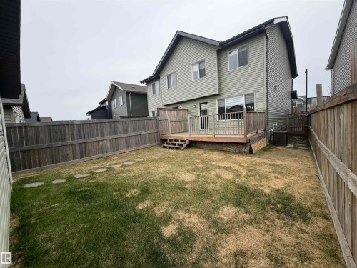 Expansive backyard featuring a wood deck with railings, privacy fencing, and a grassy area with stepping stones - 4310 Prowse Link Link, Edmonton, AB - Outdoor
