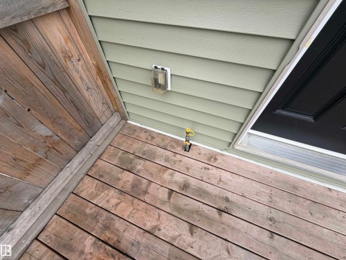 Front porch featuring wood-finish decking and light green horizontal siding - 4310 Prowse Link Link, Edmonton, AB -  With Exterior