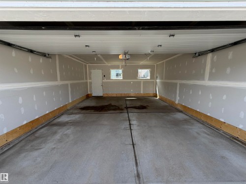 Spacious garage with concrete flooring, drywall-finished walls, and two windows providing natural light - 4310 Prowse Link Link, Edmonton, AB - Indoor Photo Showing Garage