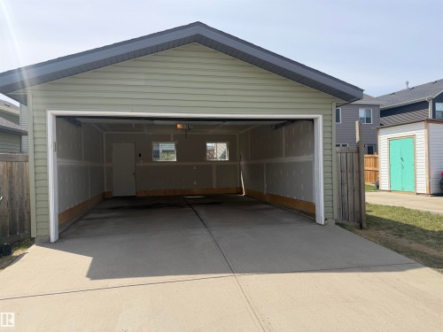 Detached double garage featuring light green siding, a dark gray roof, two interior windows, an interior access door, and a concrete floor - 4310 Prowse Link Link, Edmonton, AB - Outdoor With Exterior