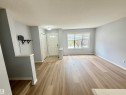 Open concept living area featuring wood-finish flooring, a contemporary ceiling light fixture, a front entry door with transom windows, and a large window with horizontal blinds - 4310 Prowse Link Link, Edmonton, AB  - Indoor Photo Showing Other Room 