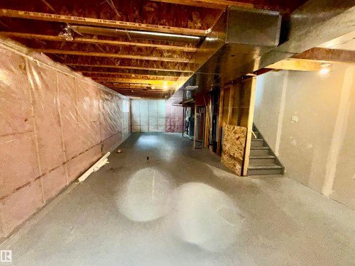 Unfinished basement space featuring exposed wood joists, concrete flooring, insulation-wrapped walls, and a visible staircase - 4310 Prowse Link Link, Edmonton, AB - Indoor Photo Showing Basement