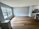 Spacious living area featuring wood-finish flooring, a large picture window with privacy blinds, and light gray wall tones - 4310 Prowse Link Link, Edmonton, AB  - Indoor 