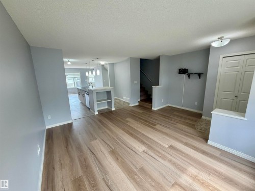 Open-concept living area featuring wood-finish flooring, light grey painted walls, and white baseboards - 4310 Prowse Link Link, Edmonton, AB - Indoor