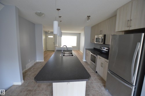 Kitchen featuring an elongated island with an undermount double-basin sink and four pendant lights - 4310 Prowse Link Link, Edmonton, AB - Indoor Photo Showing Kitchen With Double Sink