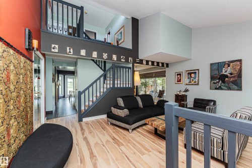 Two-story living area featuring wood-finish flooring and a central staircase with painted railings - 1235 104 Street, Edmonton, AB - Indoor