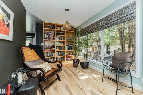 Bright space featuring expansive windows with patterned Roman shades, light wood-finish flooring, and a large built-in shelving unit - 1235 104 Street, Edmonton, AB - Indoor