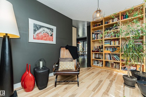 Built-in blonde wood shelving with extensive storage, light wood-finish flooring, and a modern ceiling pendant light fixture - 1235 104 Street, Edmonton, AB - Indoor