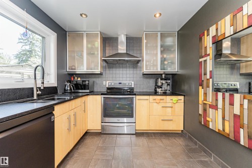 Kitchen featuring light wood-finish cabinetry, dark countertops, and a tiled backsplash - 1235 104 Street, Edmonton, AB - Indoor Photo Showing Kitchen With Stainless Steel Kitchen With Double Sink