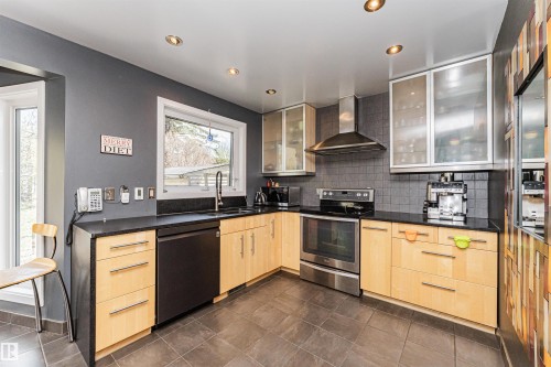 Contemporary kitchen featuring light wood-finish cabinetry, dark countertops, and a full suite of stainless steel appliances - 1235 104 Street, Edmonton, AB - Indoor Photo Showing Kitchen With Stainless Steel Kitchen With Upgraded Kitchen