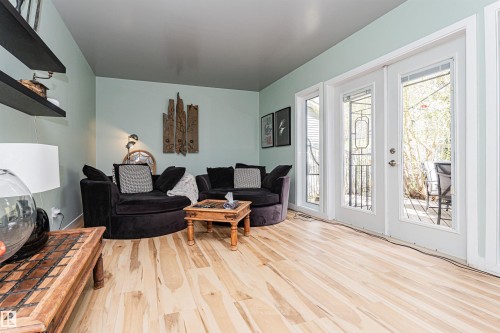 Light wood-finish flooring extending to a pair of white French doors with decorative ironwork - 1235 104 Street, Edmonton, AB - Indoor Photo Showing Living Room