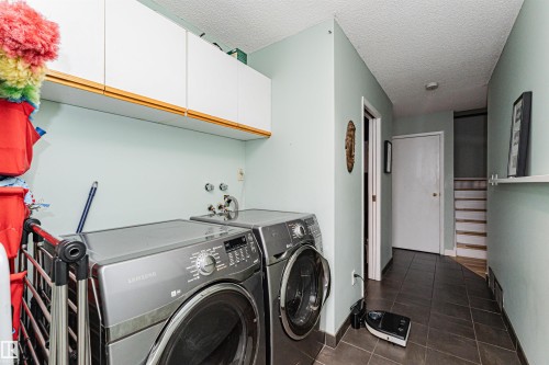 Dedicated laundry area featuring a tiled floor, overhead cabinetry, and wall-mounted water hookups - 1235 104 Street, Edmonton, AB - Indoor Photo Showing Laundry Room