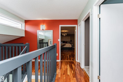 Hallway with wood-finish flooring, a contemporary wall sconce, and a full-length mirror - 1235 104 Street, Edmonton, AB - Indoor Photo Showing Other Room