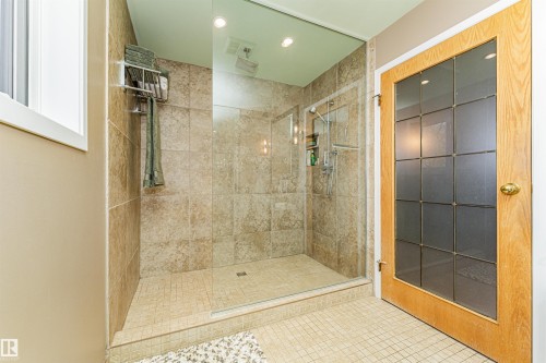 Walk-in shower with clear glass enclosure and stone-look tile surround - 1235 104 Street, Edmonton, AB - Indoor Photo Showing Bathroom