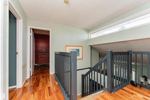 Upper-level hallway featuring wood-finish flooring, a contemporary black railing, and a transom window - 1235 104 Street, Edmonton, AB - Indoor Photo Showing Other Room