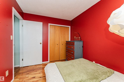 Room featuring wood-finish flooring, a bi-fold wood closet door, and a white interior door - 1235 104 Street, Edmonton, AB - Indoor Photo Showing Bedroom