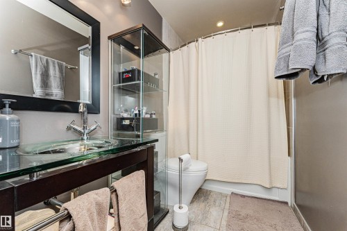 Modern vanity with a glass vessel sink, chrome faucet, and rectangular framed mirror - 1235 104 Street, Edmonton, AB - Indoor Photo Showing Bathroom