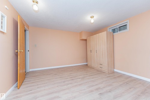 Spacious room featuring light wood-finish flooring, a light peach wall color, and white baseboards - 1235 104 Street, Edmonton, AB - Indoor Photo Showing Other Room