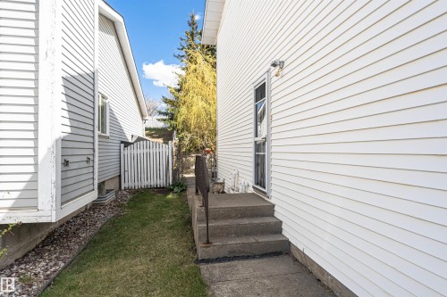 Side yard with white picket fence, concrete steps with metal railing, and a windowed exterior door - 1235 104 Street, Edmonton, AB - Outdoor With Exterior