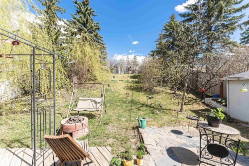 Spacious backyard featuring a tiered landscape, stone patio, and wood deck - 1235 104 Street, Edmonton, AB - Outdoor With Deck Patio Veranda
