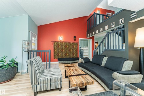 Vaulted ceilings in a living area featuring wood-finish flooring, a contemporary staircase with dark railings, and a two-story wall with varying paint colors - 1235 104 Street, Edmonton, AB - Indoor