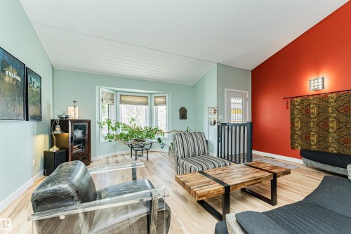Living area featuring light wood-finish flooring, a prominent bay window, and a vaulted ceiling with white paneling - 1235 104 Street, Edmonton, AB - Indoor Photo Showing Living Room