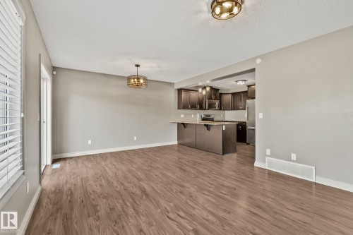 Expansive main living area featuring wood-finish flooring, a contemporary chandelier, and a sliding glass door - 46 445 Brintnell Boulevard, Edmonton, AB - Indoor Photo Showing Kitchen