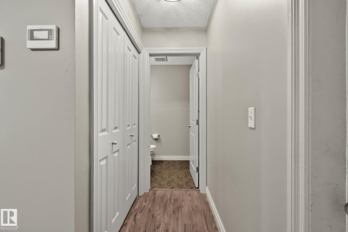 Hallway featuring wood-finish flooring, light grey painted walls, and white bi-fold closet doors - 46 445 Brintnell Boulevard, Edmonton, AB - Indoor Photo Showing Other Room