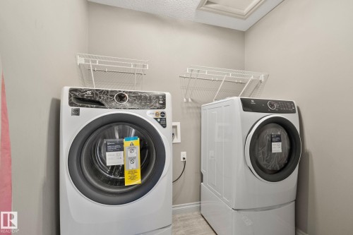 Laundry area featuring a side-by-side washer and dryer, wire shelving, and a textured ceiling - 46 445 Brintnell Boulevard, Edmonton, AB - Indoor Photo Showing Laundry Room