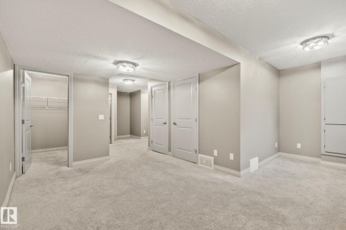 Spacious room featuring light gray carpeting, neutral wall paint, and multiple white panel doors - 46 445 Brintnell Boulevard, Edmonton, AB - Indoor Photo Showing Other Room