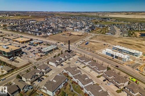 Aerial overview showcasing a residential development with multiple detached and attached properties, commercial buildings, and infrastructure - 46 445 Brintnell Boulevard, Edmonton, AB - Outdoor With View