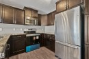 Kitchen featuring dark wood cabinetry, light-toned granite-style countertops, wood-finish flooring, and stainless steel appliances - 46 445 Brintnell Boulevard, Edmonton, AB  - Indoor Photo Showing Kitchen With Stainless Steel Kitchen With Upgraded Kitchen 