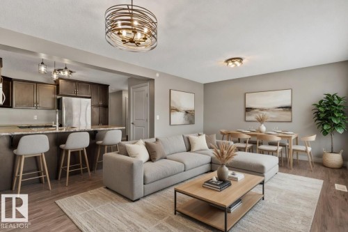 Open-concept living space featuring wood-finish flooring, a kitchen island with seating, dark wood cabinetry, and a dining area with a contemporary chandelier - 46 445 Brintnell Boulevard, Edmonton, AB - Indoor Photo Showing Living Room
