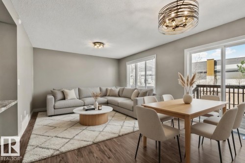 Open-concept living area with dark wood-finish flooring, light-colored walls, and a large window featuring horizontal blinds - 46 445 Brintnell Boulevard, Edmonton, AB - Indoor