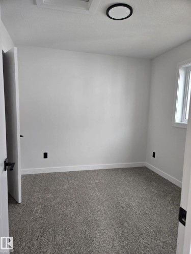 Neutral wall tones with crisp white trim, plush gray carpeting, a single window, and a contemporary ceiling light fixture - 12440 47 Street, Edmonton, AB - Indoor Photo Showing Other Room