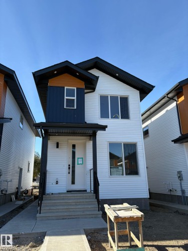 Modern facade featuring white horizontal siding, black trim, and wood-toned accents - 12440 47 Street, Edmonton, AB - Outdoor With Exterior