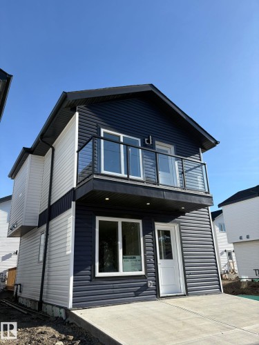 Two-tone siding exterior featuring a second-story balcony with glass railing, recessed soffit lighting, and a paved concrete patio - 12440 47 Street, Edmonton, AB - Outdoor With Exterior