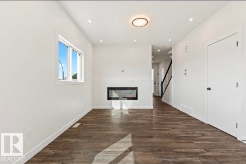 Open-concept living space featuring wood-finish flooring, a contemporary linear electric fireplace, and recessed lighting - 12440 47 Street, Edmonton, AB - Indoor With Fireplace