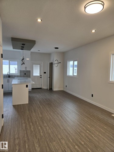 Open-concept living area featuring wood-finish flooring, recessed lighting, and a modern ceiling fixture - 12440 47 Street, Edmonton, AB - Indoor Photo Showing Kitchen