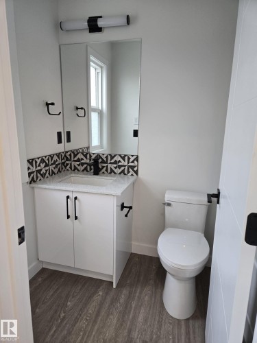 Bathroom vanity featuring a quartz countertop, integrated sink, and black and white patterned tile backsplash - 12440 47 Street, Edmonton, AB - Indoor Photo Showing Bathroom