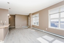 Open concept living area featuring light wood-finish flooring, neutral wall tones, and multiple large windows - 