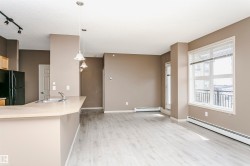 Open-concept living space with light wood-finish flooring, neutral wall tones, and a large window - 
