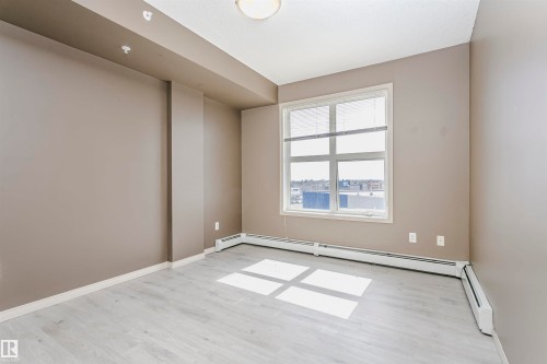 Bright room featuring light wood-finish flooring, neutral-toned walls, and a large window with horizontal blinds - 1-402 4245 139 Avenue, Edmonton, AB - Indoor Photo Showing Other Room