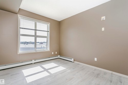 Light-toned wood-finish flooring complements neutral wall tones - 1-402 4245 139 Avenue, Edmonton, AB - Indoor Photo Showing Other Room