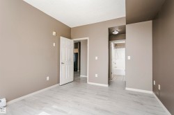 Spacious room featuring light wood-finish flooring, neutral wall paint, and white trim - 