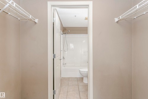 Bathroom featuring a white tub/shower combination, toilet, and tiled flooring - 1-402 4245 139 Avenue, Edmonton, AB - Indoor